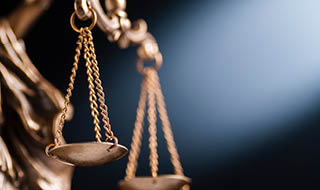 Close up on the scales of justice on a small bronze statue over a blue background with copy space conceptual of law and order