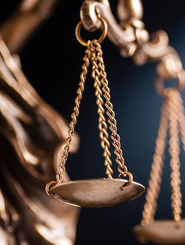 Close up on the scales of justice on a small bronze statue over a blue background with copy space conceptual of law and order